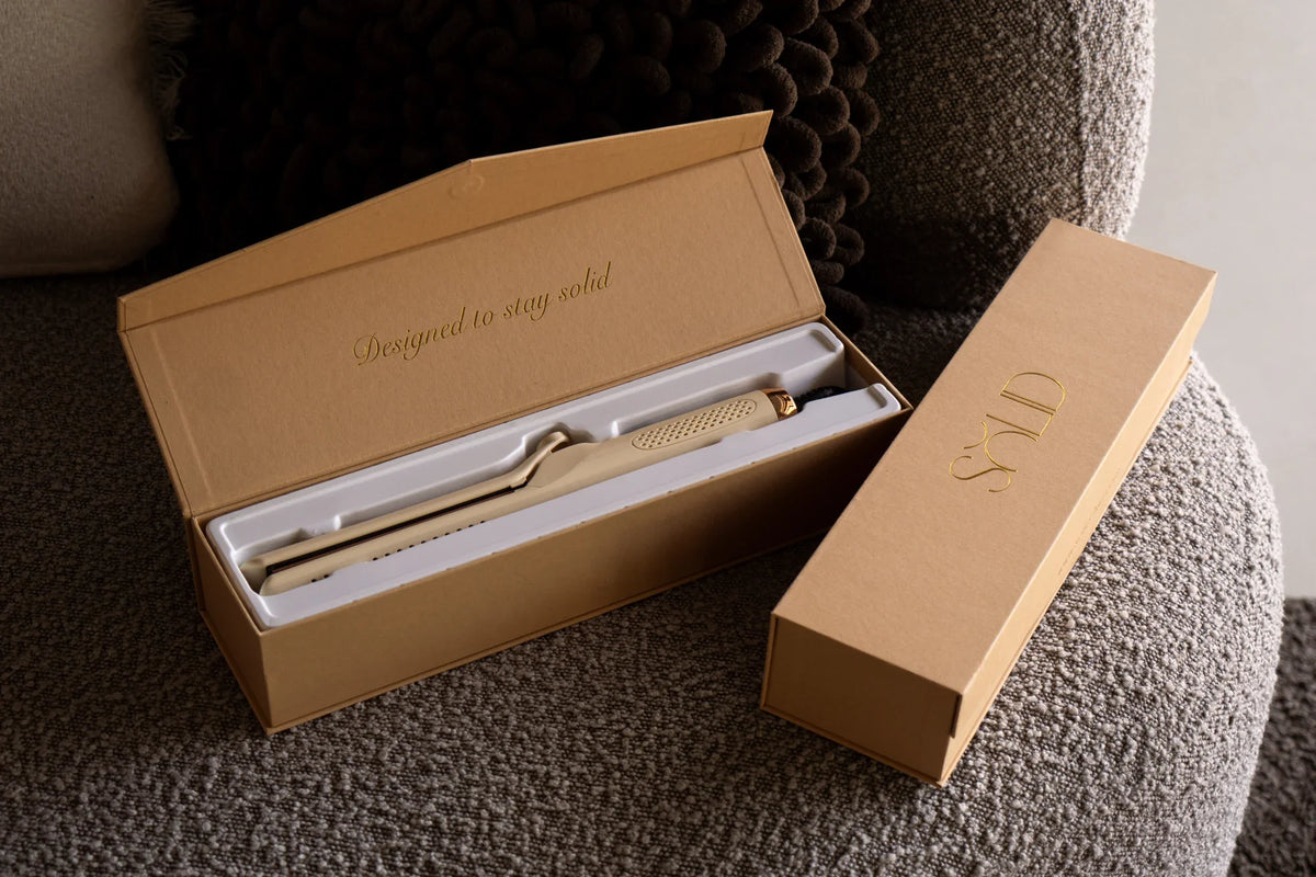 Geopende SOLID verpakking met de haarstyler op een grijze fauteuil.